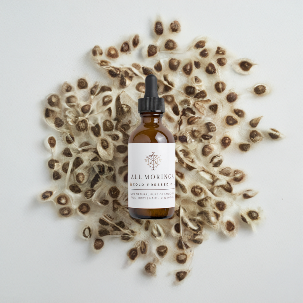 Organic Moringa seed oil bottle on top of Moringa seeds with white background