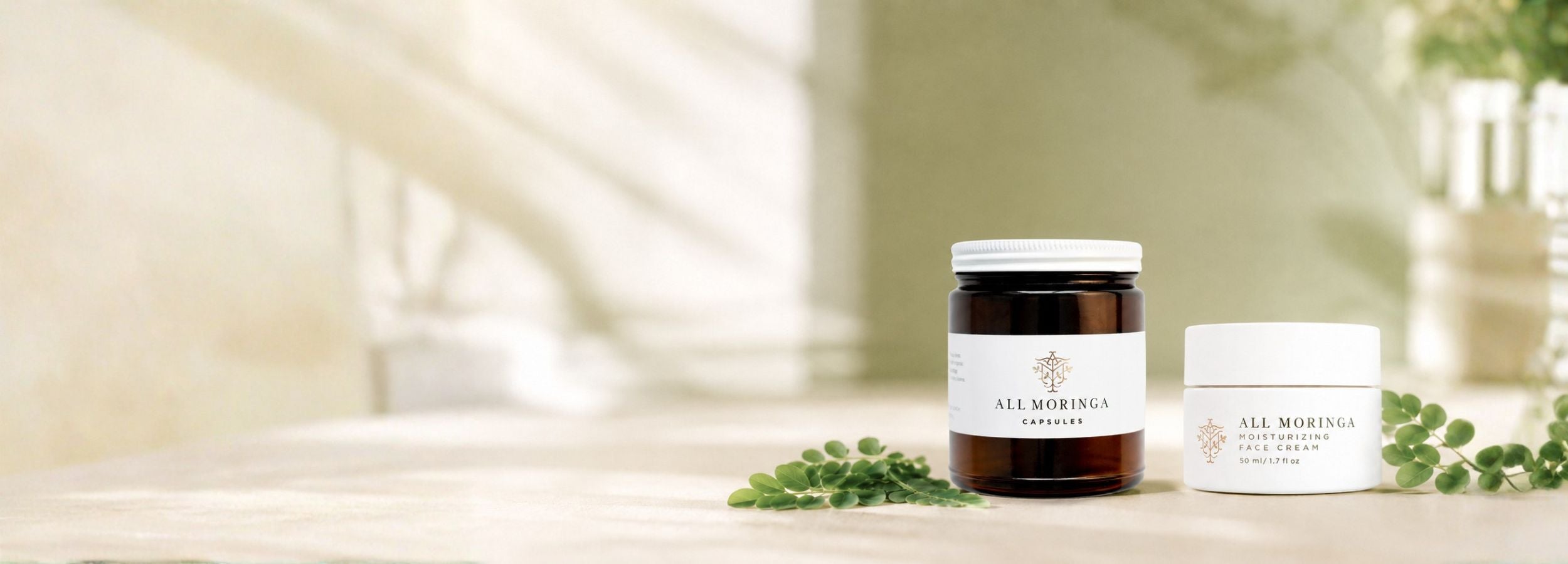 All Moringa Organic Leaf Powder pouch and Moringa Moisturizing Face Cream jar with fresh moringa leaves on a soft sage and cream surface in natural light