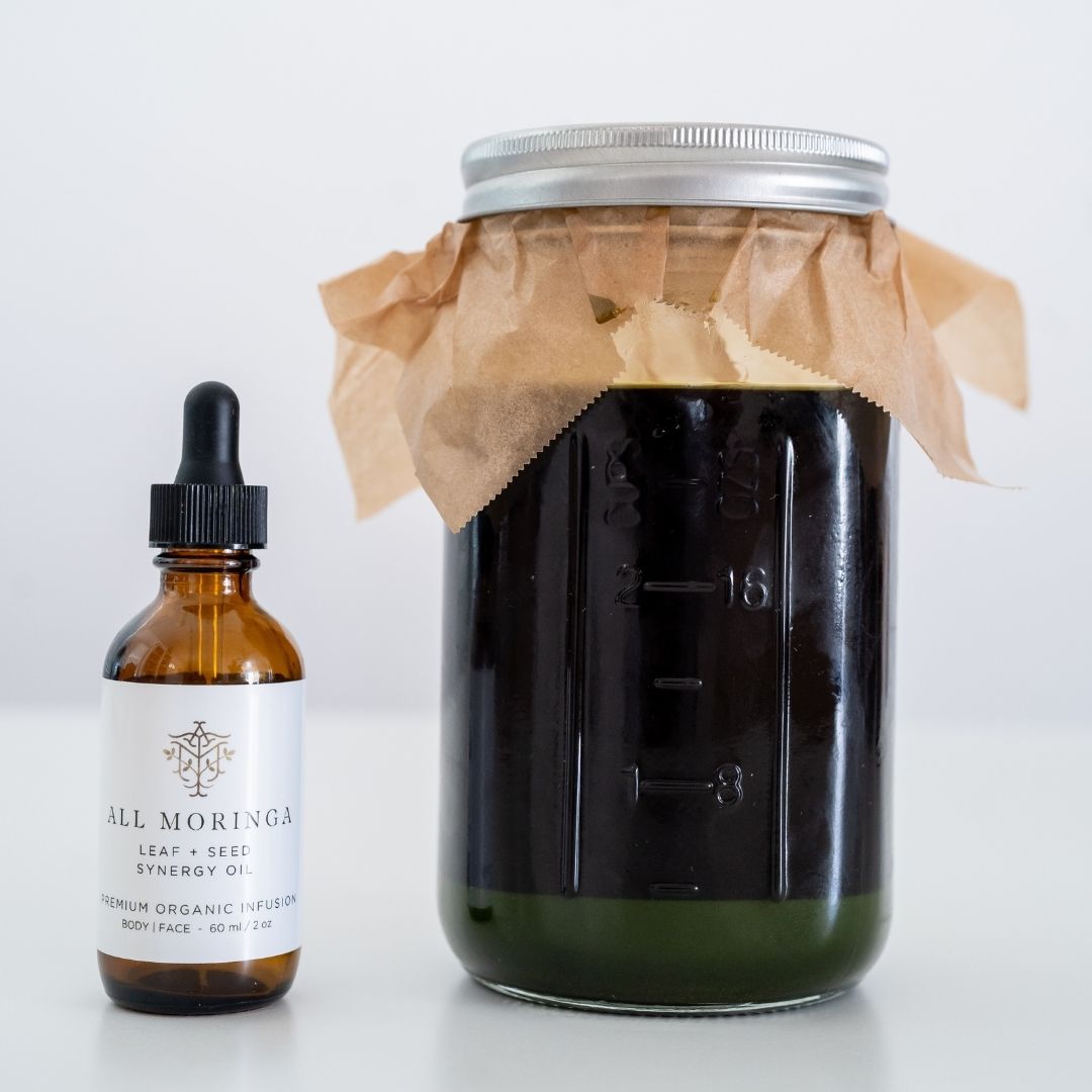 Bottle of All Moringa oil and powder oil and a jar of dark liquid on a white background