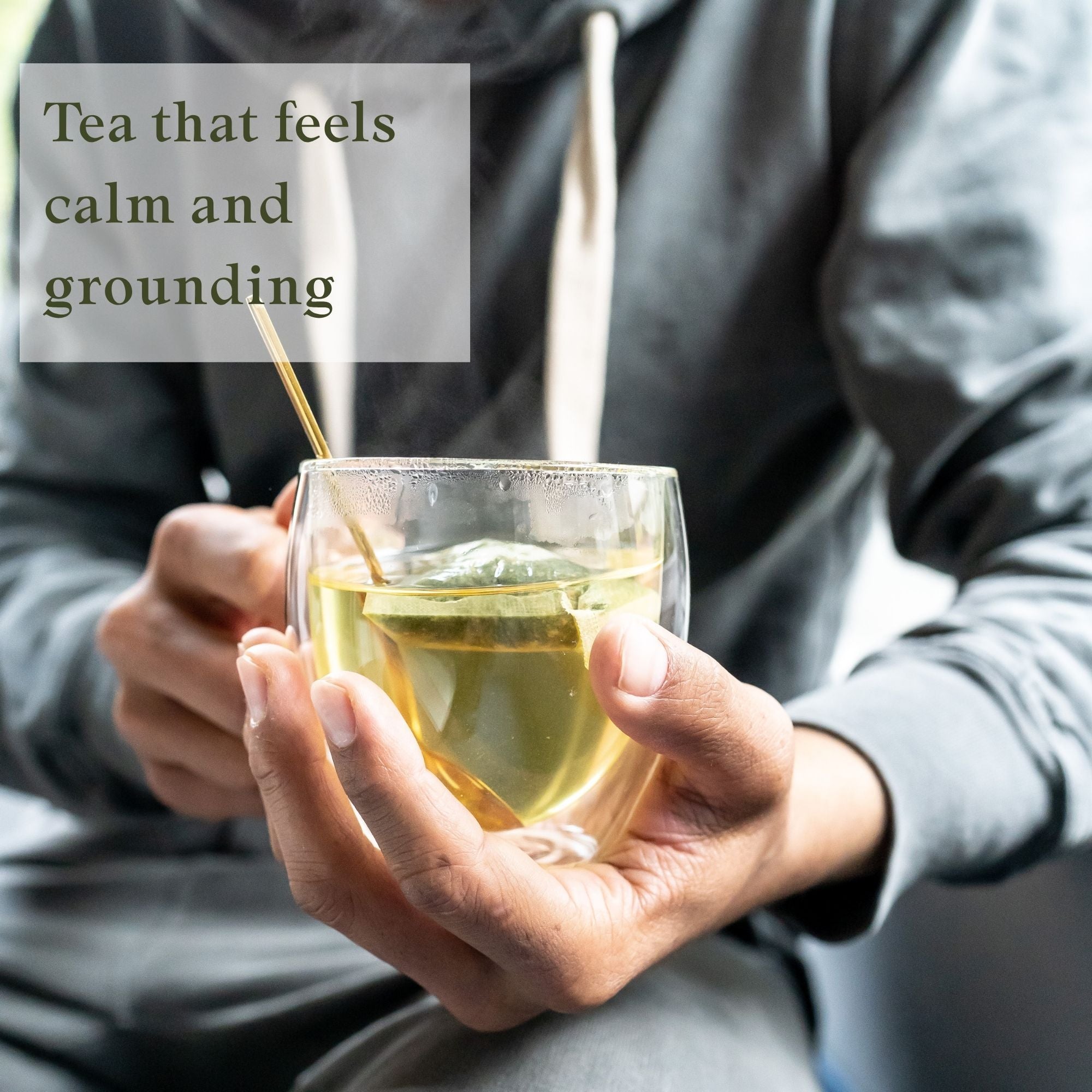 Person holding a glass of moringa leaves and ginger root tea tea with lemon and a tea spoon, 