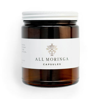 Superfood organic moringa leaves capsules in a glass jar and a metal cup with refillable pouch