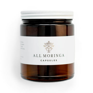 Superfood organic moringa leaves capsules in a glass jar and a metal cup with refillable pouch