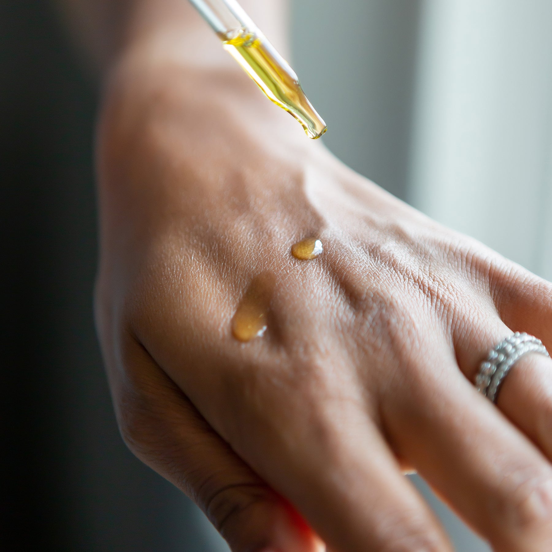 woman using organic moringa seed oil on her hand moringa drops